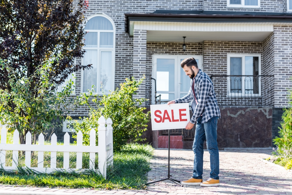 Young man with sale board selling his new house