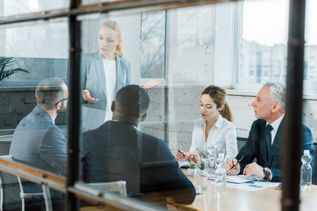 Selective focus of business coach talking while gesturing in conference room near multicultural coworkers