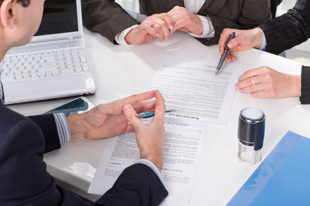 Hands of three people signing contract